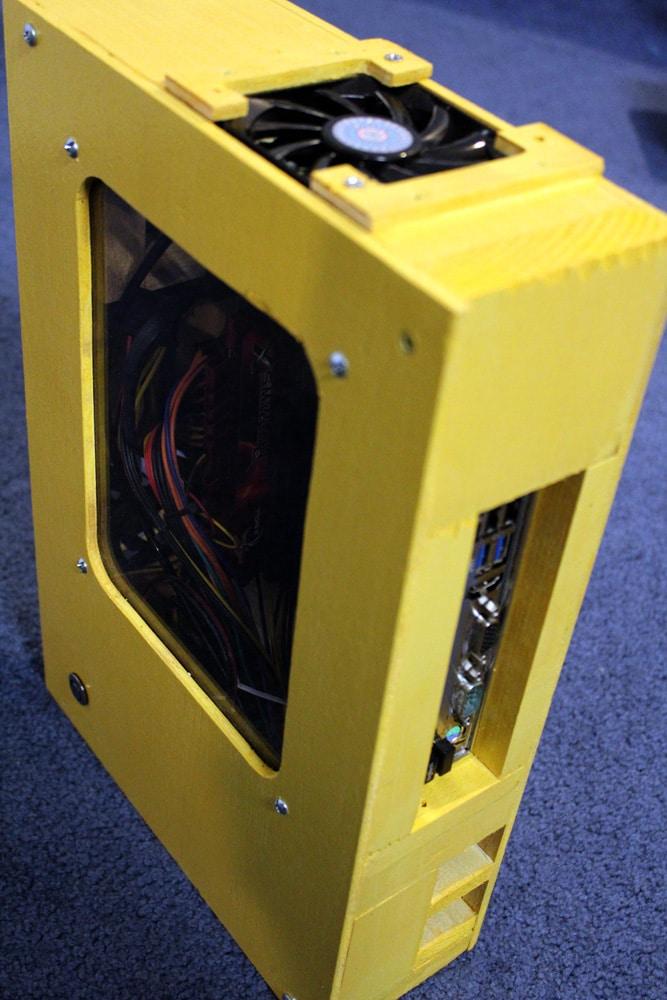 Ash's homemade computer: a yellow-painted wooden case with a window showing the wiring inside and a fan on top